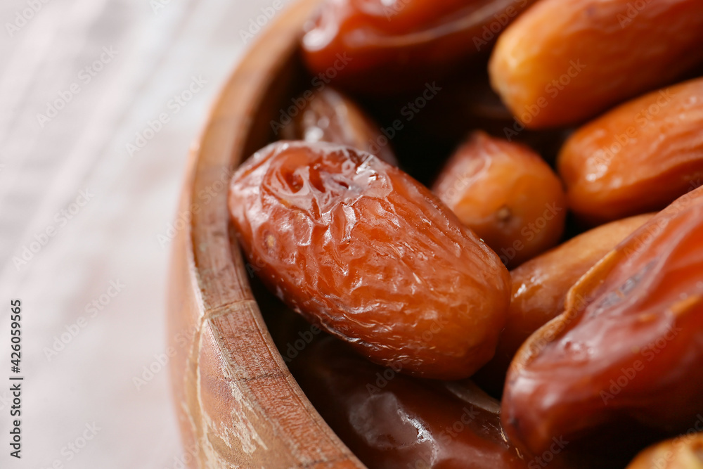 Bowl with sweet dried dates on light background, closeup