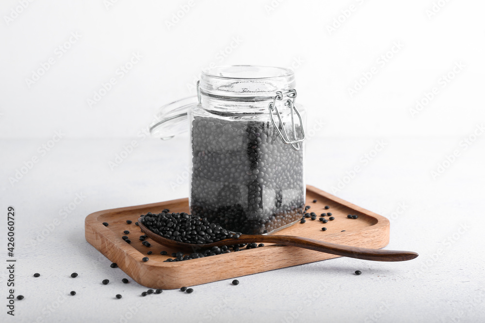 Jar of black lentils on light background