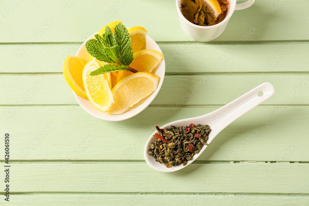 Composition with dry green tea and lemon on color wooden background