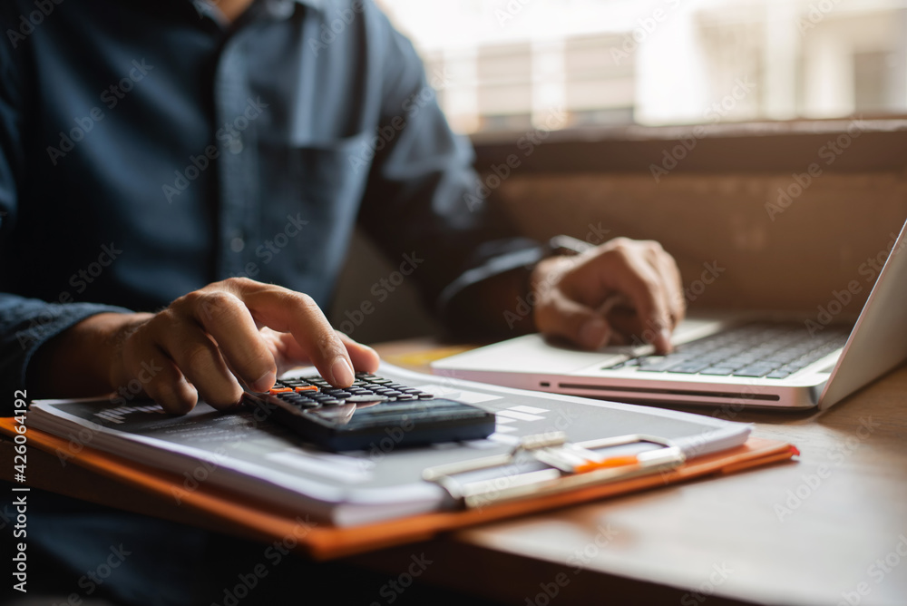 Hand businessman doing finances and calculate on desk about cost at office. - obrazy, fototapety, plakaty 