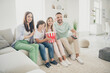 © deagreez - Full size photo of optimistic cute family brunette mom dad two kids watch tv sit on sofa wear t-shirts trousers at home