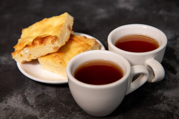 Two cups with tea, cottage cheese casserole on a saucer. Breakfast. Close-up. Selective focus.