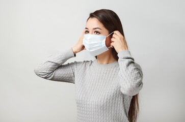 Poster - Young woman wearing medical mask, white background.