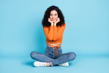 Sticker - Full size photo of young woman happy positive smile hands touch chin dream dreamy sit floor isolated over blue color background