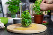 © PhotoHunter - Basil leaves thrown into a blender. Prepare basil pesto.