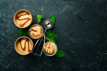 Caramel ice cream with mint and salted caramel. Ice cream spoon. On a black stone background, top view.