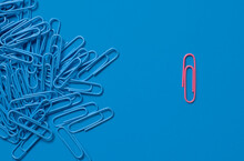 One Pink Paper Clip And Pile Of Blue Paper Clips