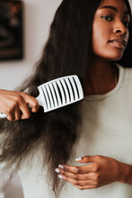 Charming African Female Brushing Her Long Black Hair With A White Comb