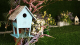 Fototapeta Krajobraz - Decorative nesting boxes on bright background. Blue birdhouse on green background