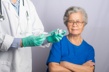 Doctor giving an injection to a senior woman in the hospital. Selective focus. Senior vaccination concept