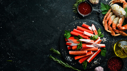 Wall Mural - Crab sticks from a crab on a black stone plate. Rustic style. Seafood delicacies.