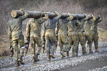 Special Forces Military Training Carrying A Big Log. Photograph Detail With Military Equipment And Assault Rifle.