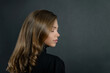 attractive young blonde girl with beautiful blonde natural hair curls on a black background copy space. portrait of a beautiful elegant woman in profile