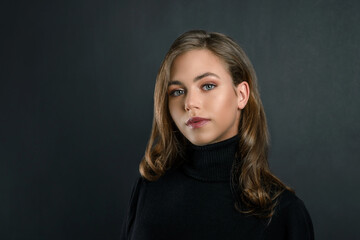 beautiful young blonde girl close up in black clothes on a black background. portrait of a beautiful elegant woman