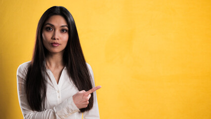 Wall Mural - Female asian model points to something - studio photography