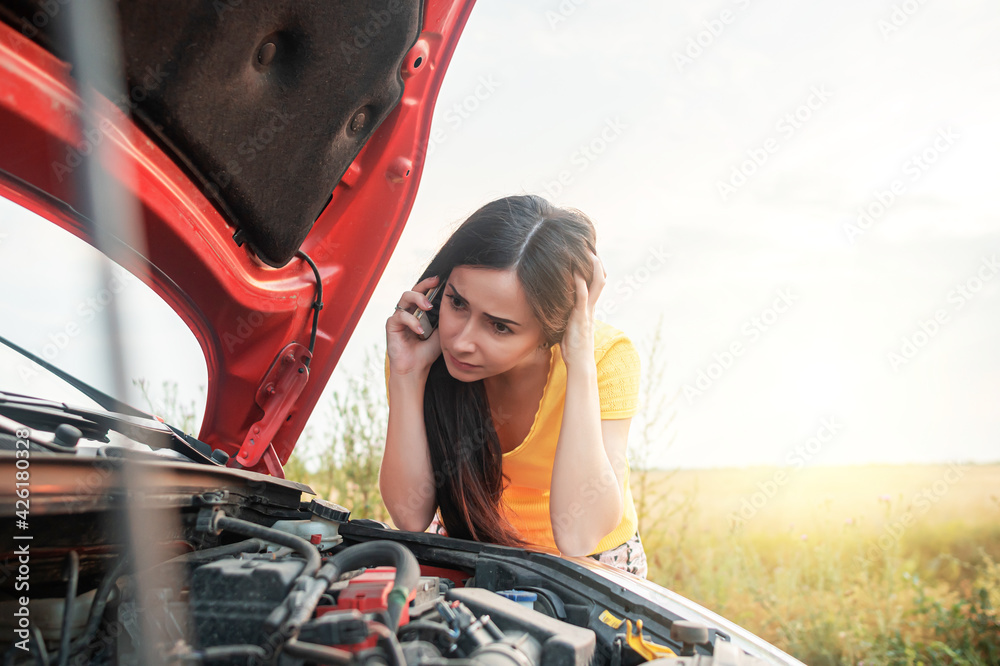 Car breakdown. Young woman calls on the phone while standing by a ...