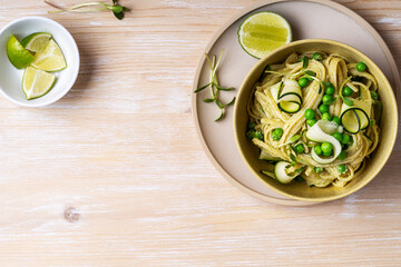 Poster - Bowl of linguine pasta with avocado sauce, green peas, zucchini, sprouts on rustic wood table