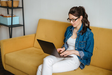 Businesswoman typing an e-mail on laptop at home office.