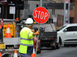 Male construction road worker holding a stop sign and directing traffic on the street. Traffic management