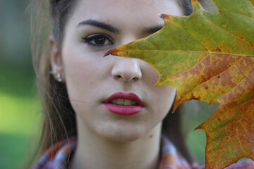 Closeup shot of a young caucasian female posing with a leaf