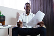 © Wavebreak Media - Casual african american businessman holding pen and document sitting in armchair