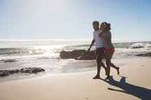 Happy African American Couple Walking On Beach Embracing