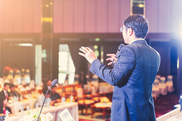 Asian businessman giving speech presentation stage meeting hall conference professional boss chief executive officer company talk lecture seminar coaching educator with people audience in background