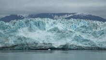 Panning Shot Of Huge Hubbard Glacier In Alaska, USA On A Dark Cold Gloomy Overcast Cloudy Day With Huge Snow Capped Mountains In The Background