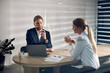 © Drazen - Businessman talking to female coworker while using laptop during a meeting in the office.
