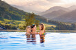 © famveldman - Family in swimming pool with mountain view
