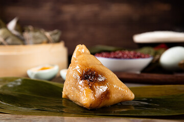 Poster - Closeup of zongzi on leaves on the table with ingredients on a blurry background