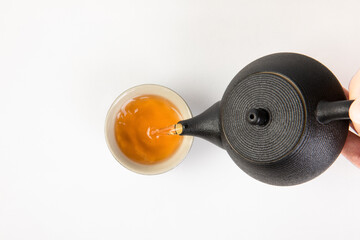 Poster - Hand pouring a tea from a teapot isolated on a white background