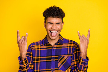 Photo portrait of young man smiling showing heavy metal gesture tongue crazy isolated bright yellow color background