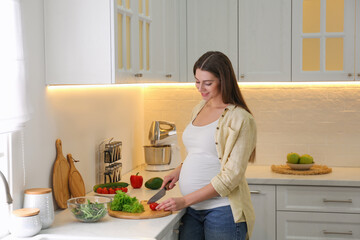 Canvas Print - Young pregnant woman preparing vegetable salad at table in kitchen. Healthy eating