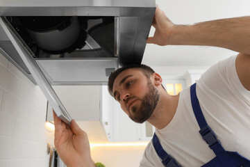 Poster - Worker repairing modern cooker hood in kitchen