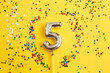 © stopabox - five years birthday party. number five with multicolored confetti in the form of stars on a yellow background