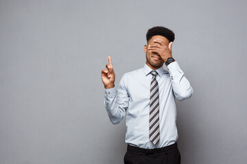 Wall Mural - Business Concept - Confident thoughtful young African American pointing finger on side over grey background.