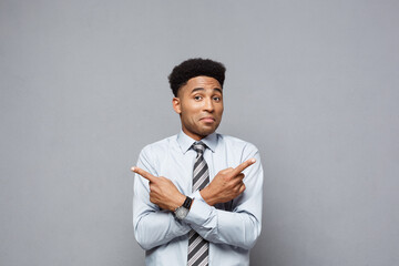 Wall Mural - Business Concept - Confident thoughtful young African American pointing finger on side over grey background.