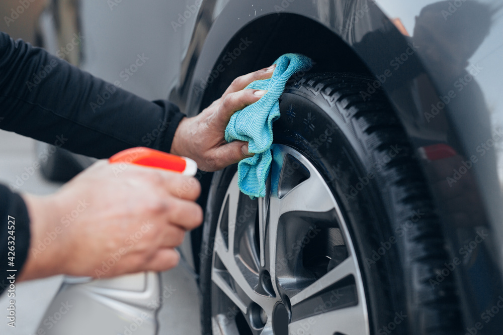 close up man cleaning car tires in carwash service - obrazy, fototapety, plakaty 