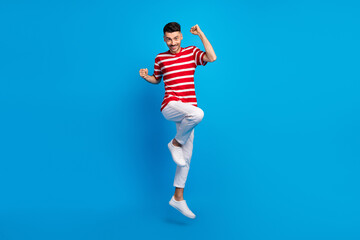 Wall Mural - Full size photo of nice brunet hooray guy jump wear red t-shirt trousers sneakers isolated on vivid blue color background