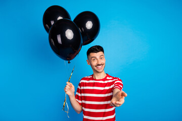 Poster - Photo of happy attractive positive young man invite you good mood hold balloons decoration isolated on blue color background