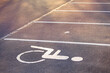 Empty parking lot, white lines on the asphalt, sunny day. Handicapped parking space at a parking lot outside a building, icon, sign painted on the designated parking space for disabled persons.
