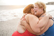 © DisobeyArt - Plus size women having fun on the beach hugging each other during summer vacation - Focus on right face