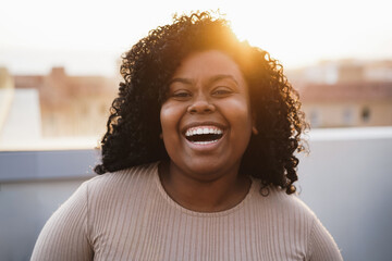 Happy young african girl looking at camera outdoors at summer sunset - Focus on face