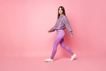 Wall Mural - Full body profile portrait of adorable lady walking beaming smile look camera isolated on pink color background