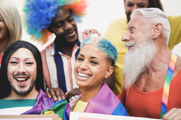 Multiracial gay people having fun at pride parade with LGBT flags and banners outdoors - Main focus on lesbian face