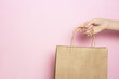 Girl holding in hand beige craft paper bag for shopping on pink background. Shopping concept