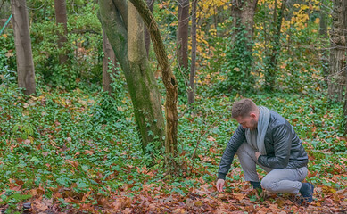 young man bending down to pick up leaves from the ground