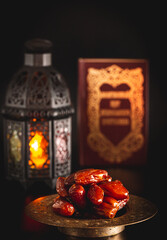 Wall Mural - Dried dates with an open Muslim holy book Quran. The Muslim holiday of the holy month of Ramadan Karim on a dark background. Beautiful background with shining Fanuc lantern