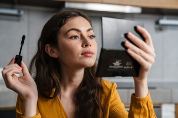 Smiling young brunette woman doing makeup